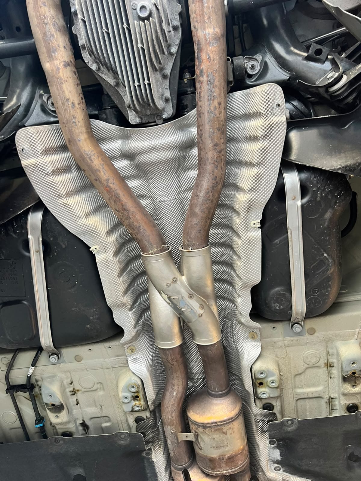 Një Z-Pipe i montuar, parë nga poshtë në lift: dy gypat zbresin mbi mburojën e nxehtësisë dhe bashkohen në një degëzim inoksi me pllakën ADT të prerë me lazer.